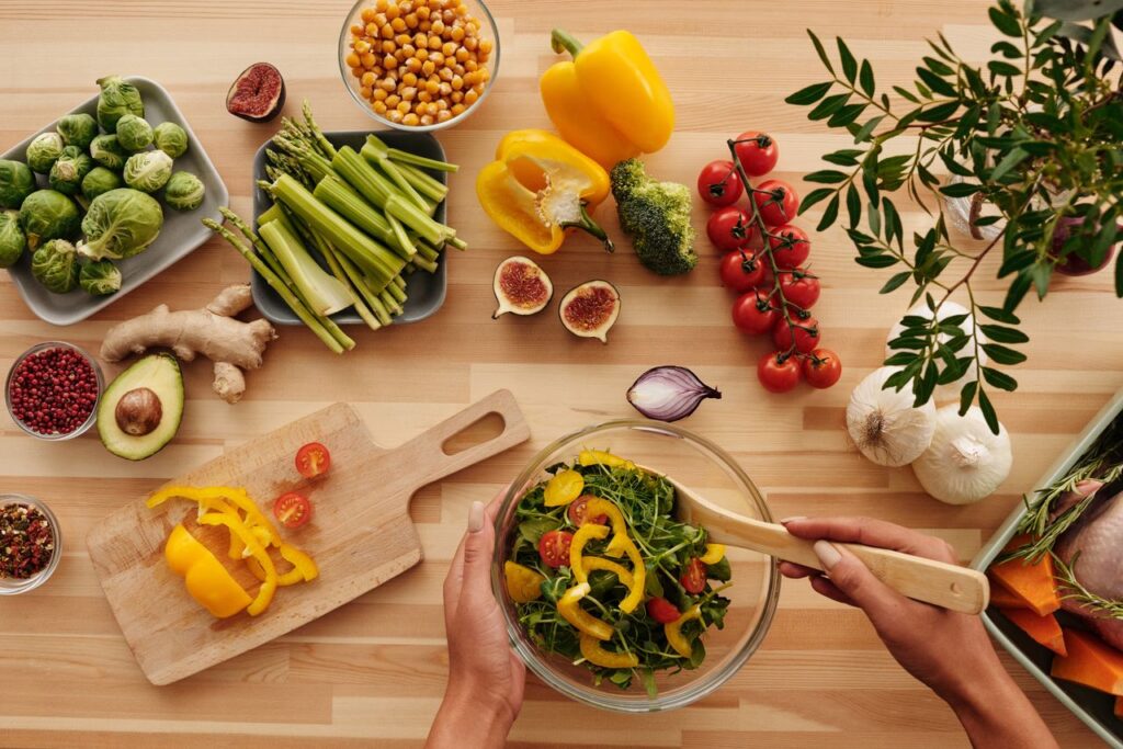Top view of fresh vegetables and salad preparation on a wooden table, perfect for healthy eating concepts.